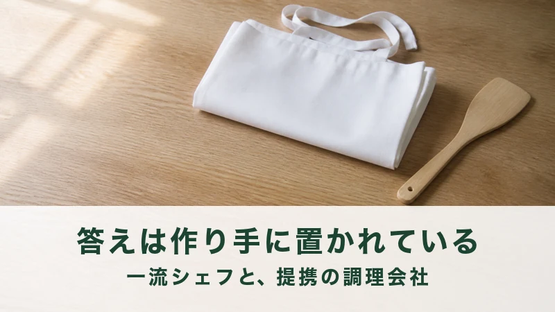 木の作業台にたたんだ白い前掛けと木のへらが一本