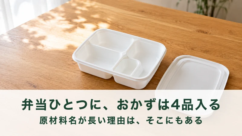 木のテーブルに置かれた仕切りのある白い弁当容器