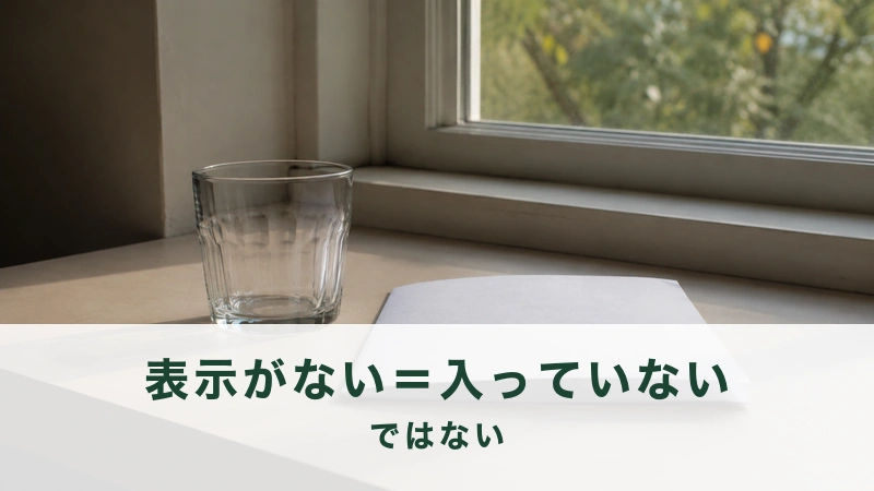 午後の窓辺に空のグラスがひとつと白い紙が一枚置かれている