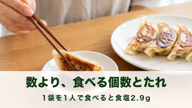 小皿のたれに焼き餃子を箸でつけようとしている手元