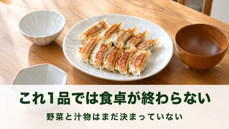 食卓の中央に焼き餃子の皿があり小鉢は空のままの場面