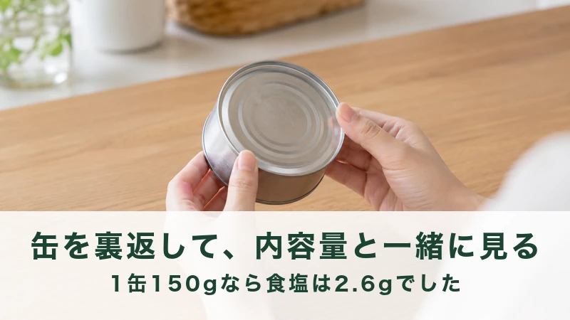 銀色の缶を裏返して底を見ている手元