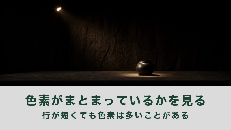 暗い部屋の台に黒い丸壺が一つ灯りに光る