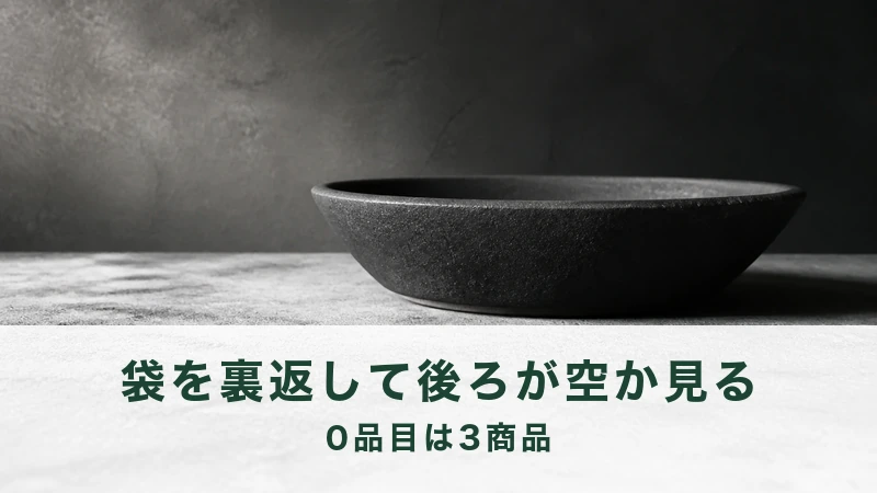 暗い壁を背に黒い浅い鉢を1つ置いた