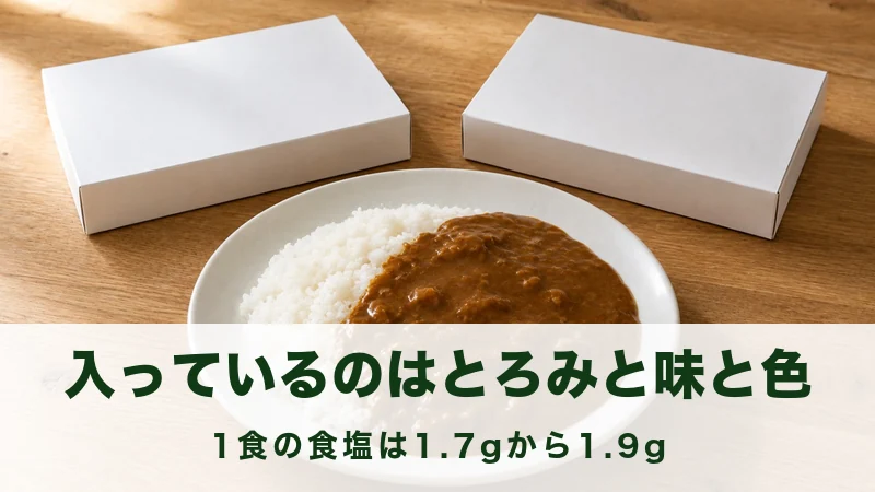 テーブルに無地の白い紙箱2つと、ごはんにソースをかけた皿
