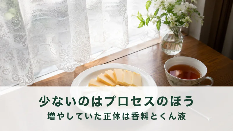 窓辺の木のテーブルに白い皿のチーズと紅茶のカップが置かれている