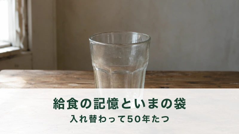 古い木の机に置かれた、少し曇った背の高いガラスのコップがひとつ