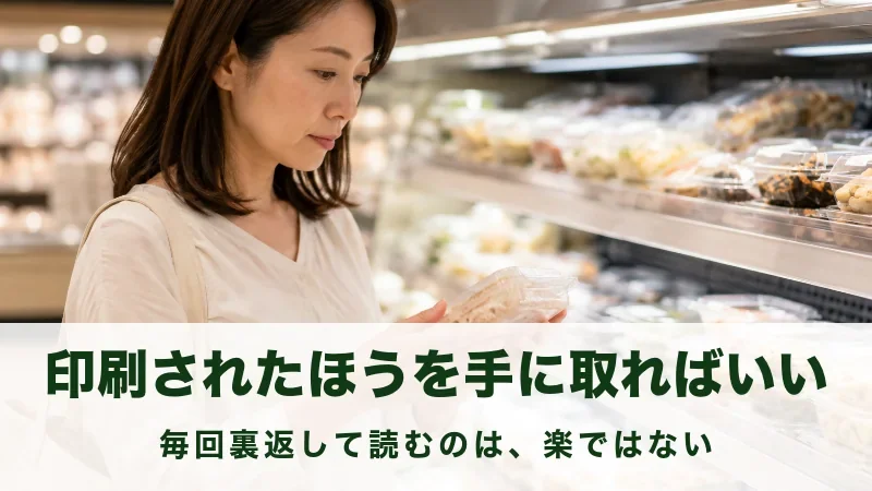 売り場で惣菜のパックを裏返して見ている女性