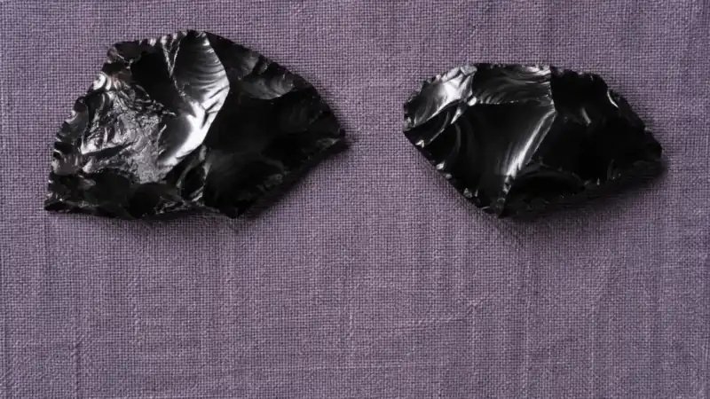 紫がかった布の上に、黒く光る石のかけらを2つ置いた
