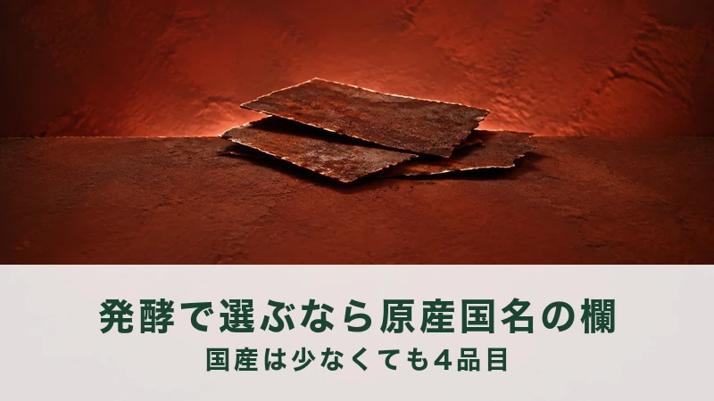 赤い壁に照らされた台に、錆びた薄い鉄の板を3枚、ずらして重ねた