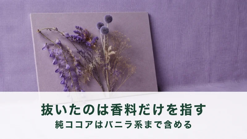 薄紫の壁に立てかけた板の上で、乾いた紫の花が数本ひらいている