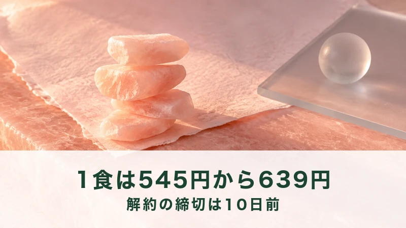 桃色の紙の上で岩塩のかけらを4つ積み上げ、右にガラスの玉が置いてある