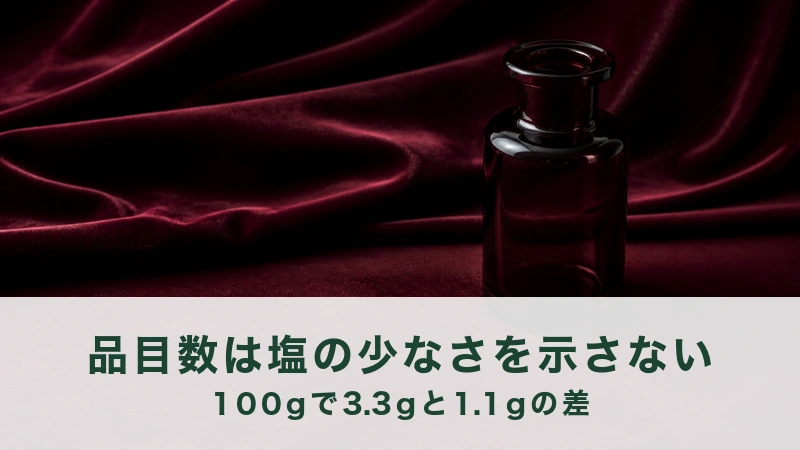深紅の布のひだの前に、中を空にしたボルドーのガラス瓶が一本