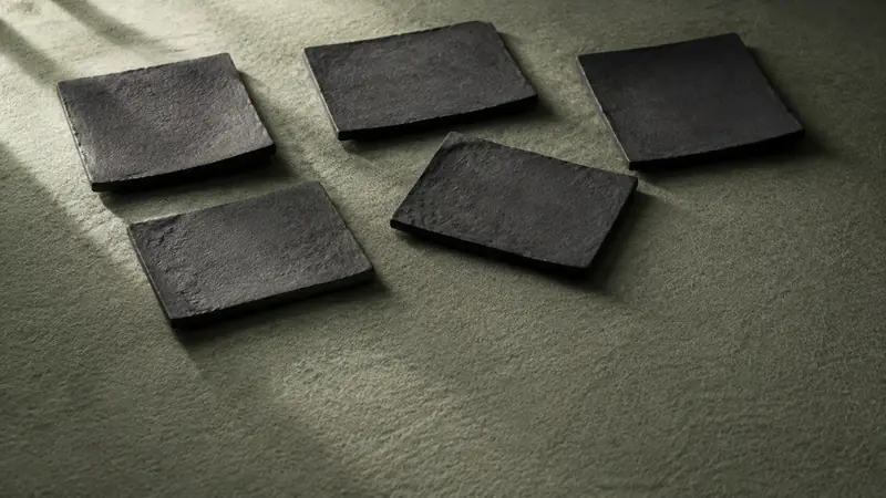 緑の面に黒い薄い板が五枚、間を空けて散らばっている