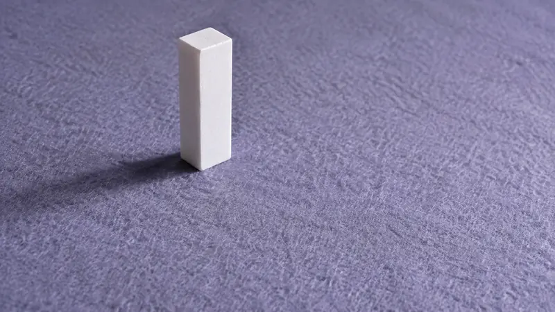 薄紫の布の上に立てた白い直方体のブロック一つ