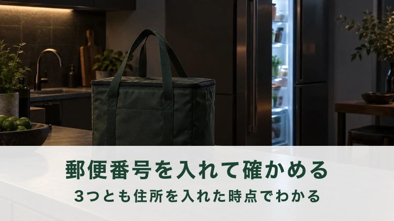 夜の台所に置かれた保冷バッグと、明かりの点いた冷蔵庫
