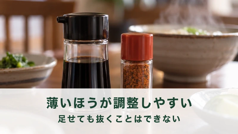 食卓に置かれた醤油差しと七味の小瓶、湯気の立つ器